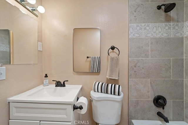 full bathroom featuring tiled shower / bath, vanity, and toilet