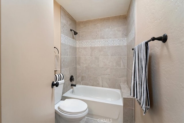 bathroom with tiled shower / bath combo and toilet