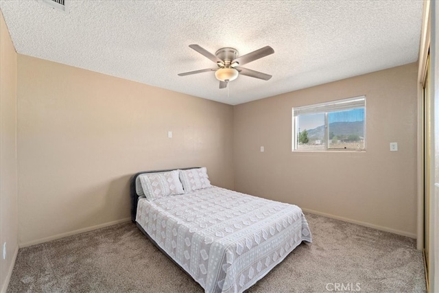 bedroom featuring light carpet, a textured ceiling, and ceiling fan