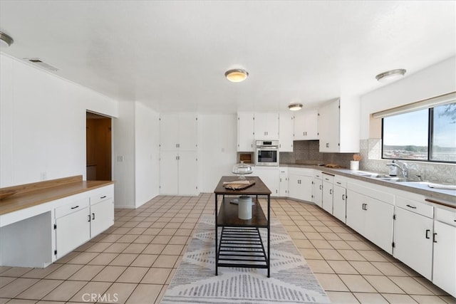 kitchen featuring backsplash, sink, oven, and white cabinets