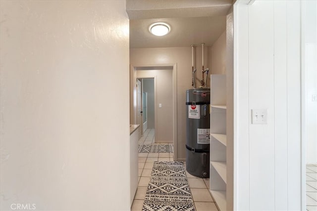 corridor featuring water heater, light tile patterned floors, and a textured ceiling