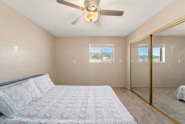 carpeted bedroom featuring a textured ceiling, a closet, multiple windows, and ceiling fan