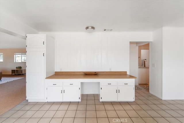 kitchen featuring white cabinets, built in desk, and light tile patterned floors