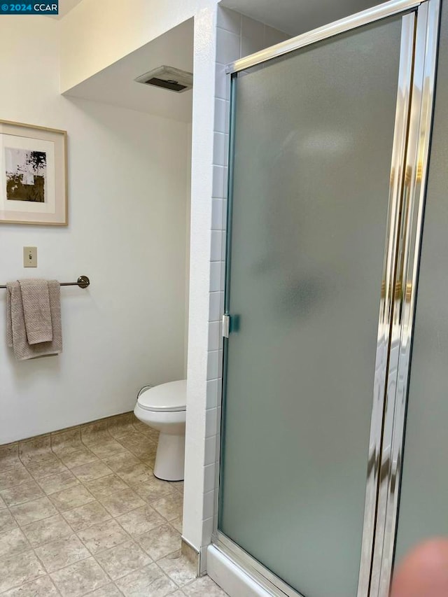 bathroom featuring tile patterned floors, toilet, and walk in shower