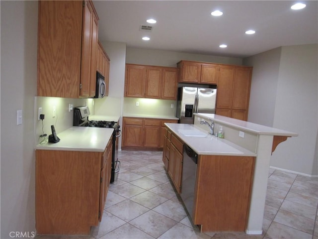 kitchen featuring sink, stainless steel appliances, a kitchen island with sink, a breakfast bar, and light tile patterned floors