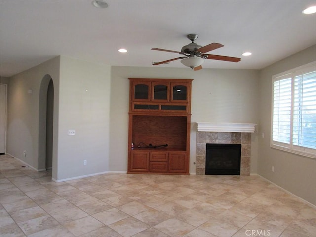 unfurnished living room with ceiling fan and a tiled fireplace