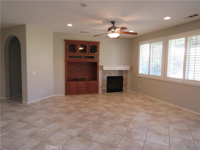 unfurnished living room with a tile fireplace, ceiling fan, and light tile patterned flooring