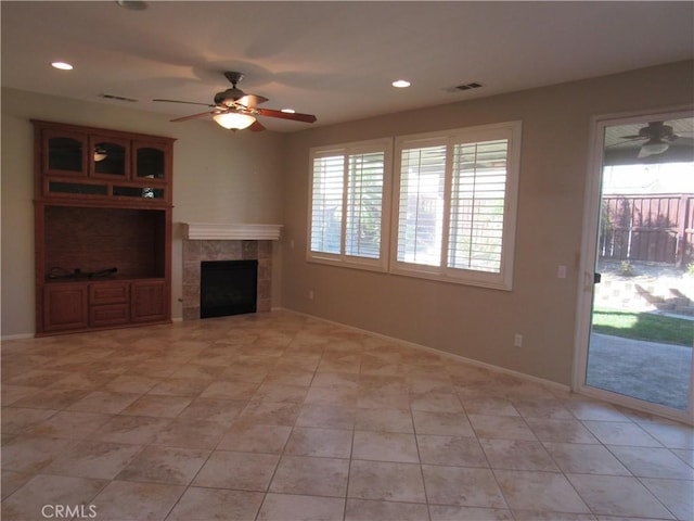 unfurnished living room featuring plenty of natural light, ceiling fan, light tile patterned flooring, and a tiled fireplace