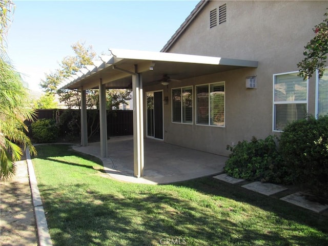 back of property with ceiling fan, a yard, and a patio