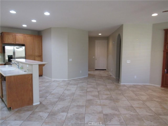 kitchen with a kitchen bar, stainless steel fridge, and sink