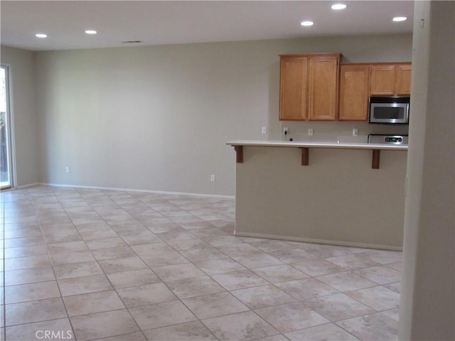 kitchen with a kitchen bar, appliances with stainless steel finishes, and kitchen peninsula