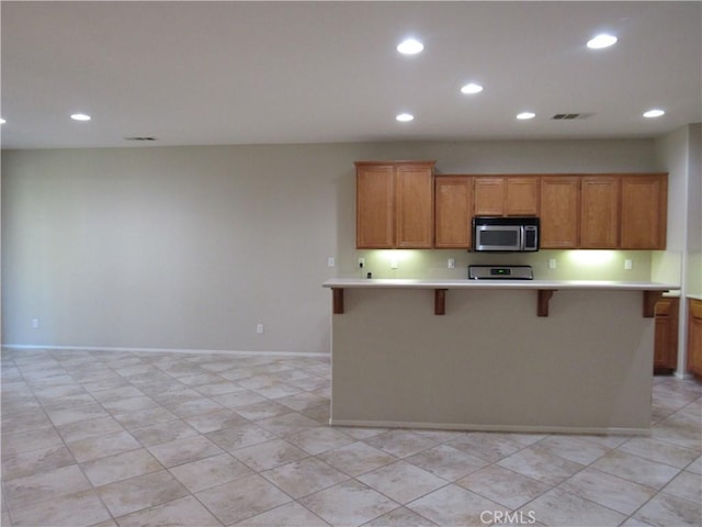 kitchen featuring a kitchen bar, appliances with stainless steel finishes, and a kitchen island with sink