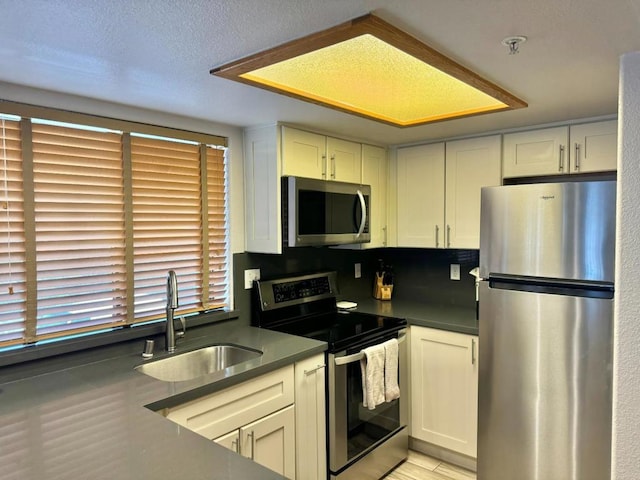 kitchen featuring white cabinets, appliances with stainless steel finishes, sink, and a textured ceiling