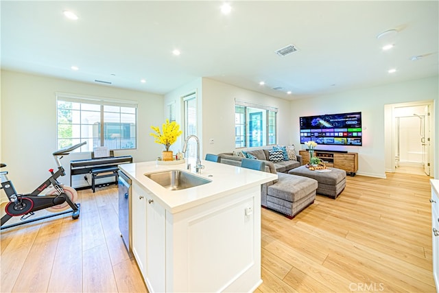 kitchen featuring light hardwood / wood-style flooring, a center island with sink, sink, and white cabinetry