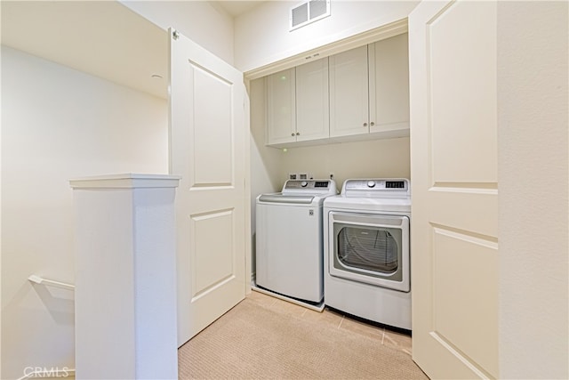 laundry room featuring light carpet, separate washer and dryer, and cabinets