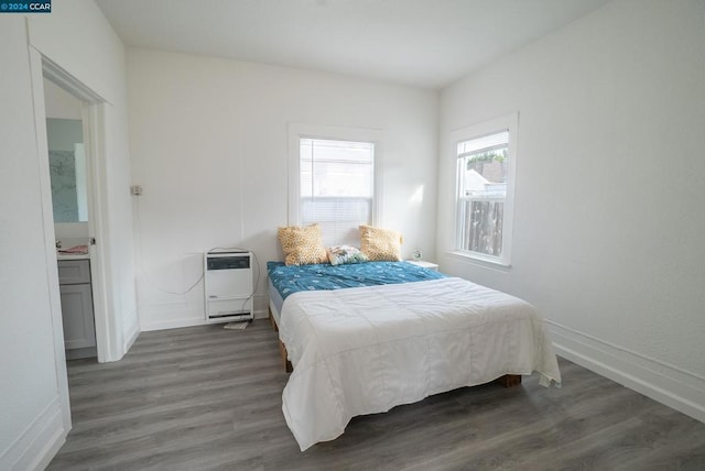 bedroom featuring heating unit and dark hardwood / wood-style floors