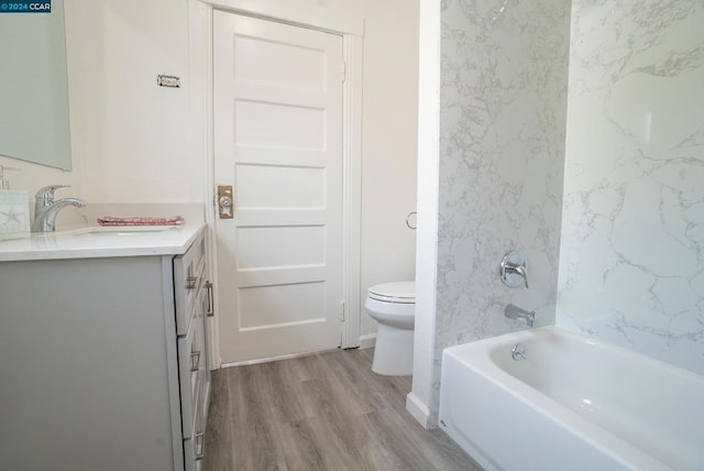 full bathroom with hardwood / wood-style floors, vanity, tiled shower / bath combo, and toilet