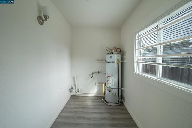 clothes washing area with secured water heater and wood-type flooring