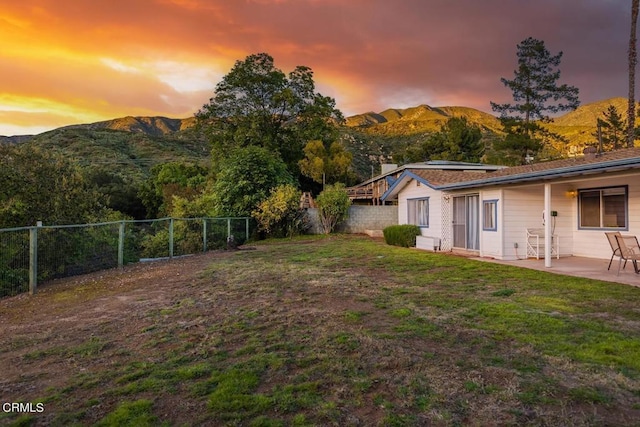 yard at dusk with a patio area and a mountain view