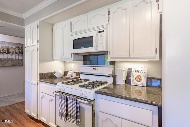 kitchen with white cabinetry, dark stone countertops, light wood-type flooring, white appliances, and ornamental molding