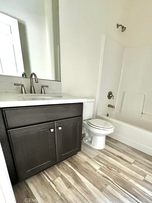 full bathroom with hardwood / wood-style floors, shower / washtub combination, vanity, and toilet