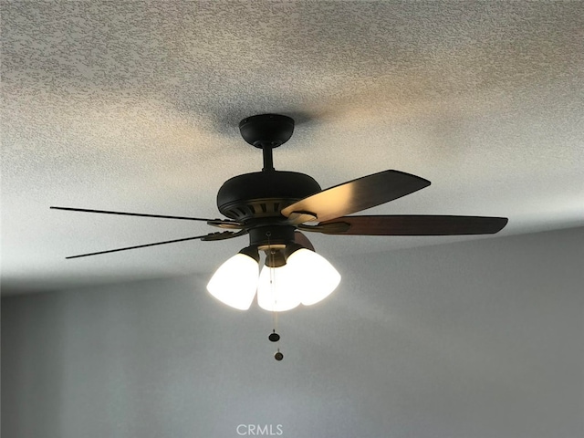 room details with ceiling fan and a textured ceiling