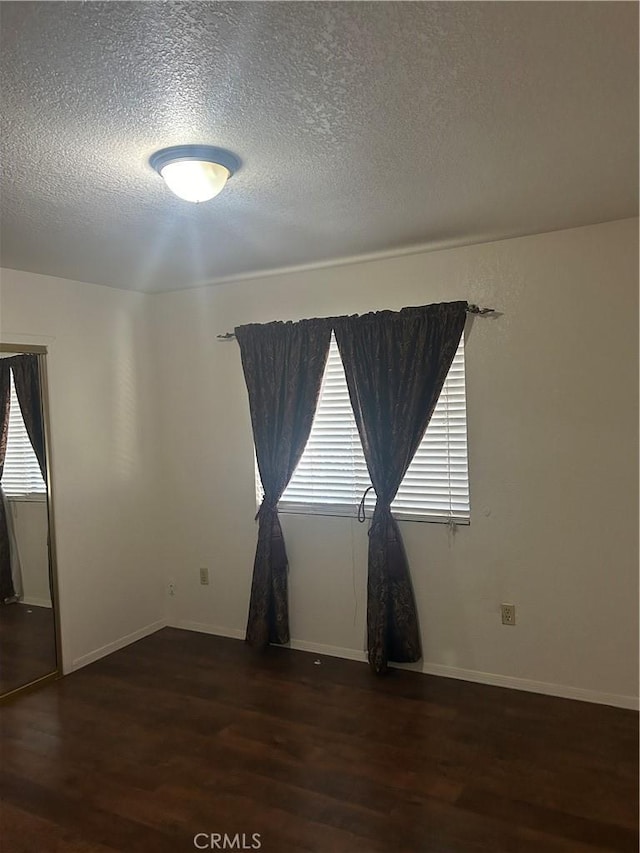 spare room with dark hardwood / wood-style floors, plenty of natural light, and a textured ceiling