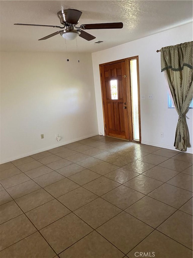 tiled entryway featuring a textured ceiling and ceiling fan