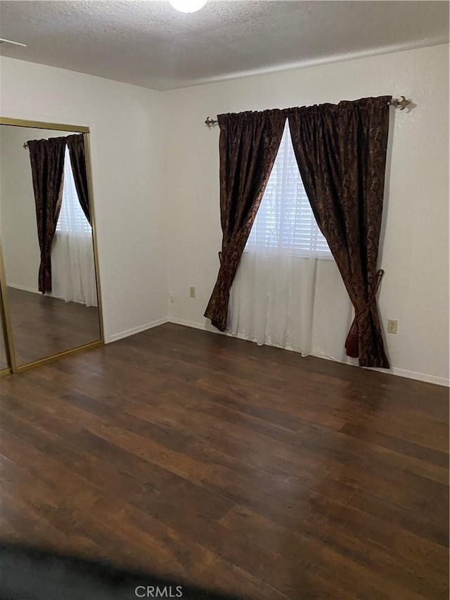 unfurnished room with dark wood-type flooring and a textured ceiling