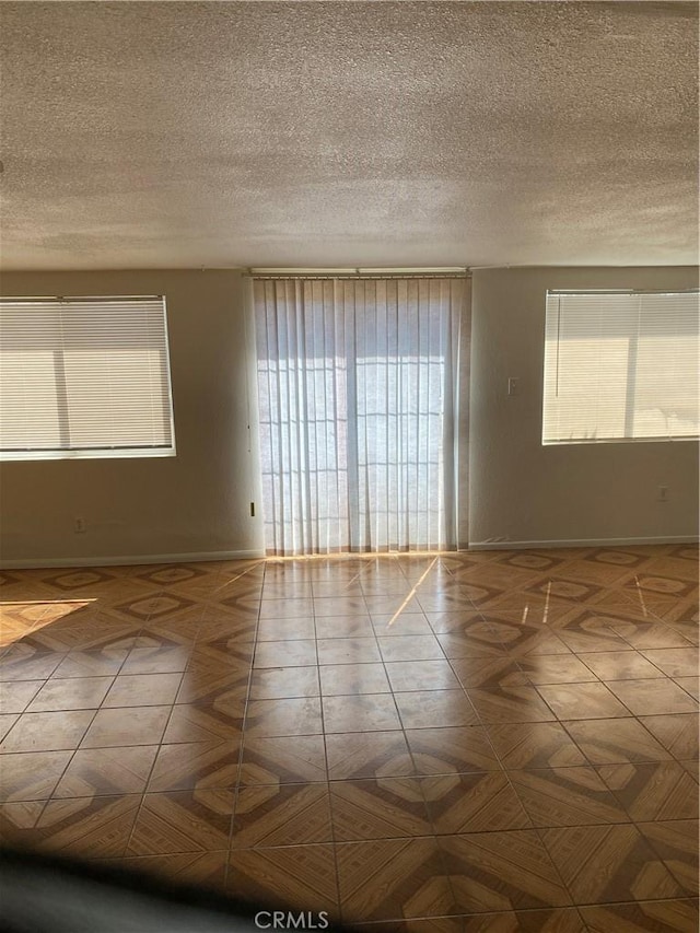 unfurnished room featuring parquet flooring and a textured ceiling