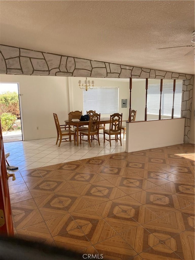 tiled dining area featuring ceiling fan with notable chandelier and a textured ceiling