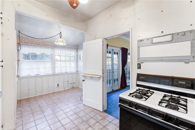 kitchen with a wealth of natural light, decorative light fixtures, white gas stove, and white cabinetry