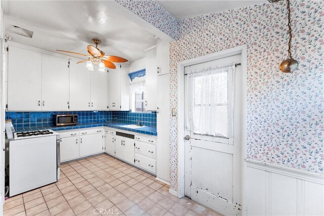 kitchen with decorative backsplash, white stove, sink, white cabinetry, and tile countertops