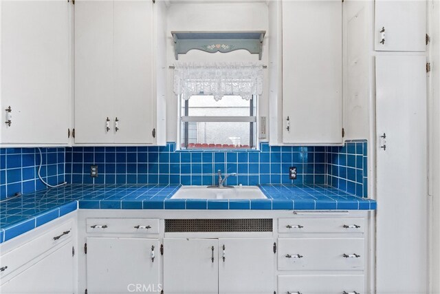 kitchen with tasteful backsplash, tile countertops, and white cabinetry