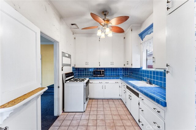 kitchen with white cabinets, tile countertops, tasteful backsplash, and white gas range oven