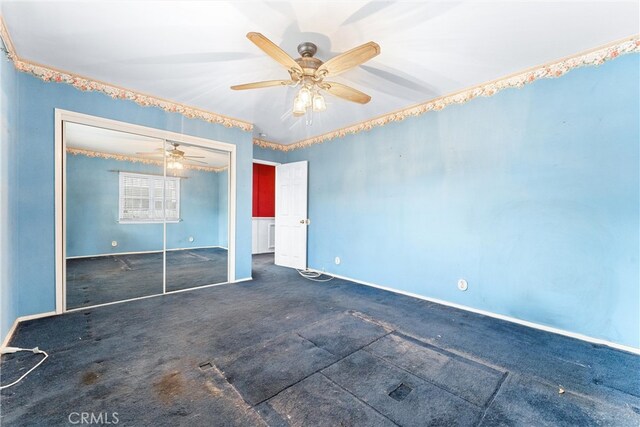 unfurnished bedroom featuring ceiling fan, a closet, and dark colored carpet