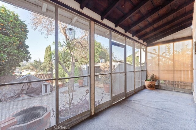 unfurnished sunroom with vaulted ceiling with beams