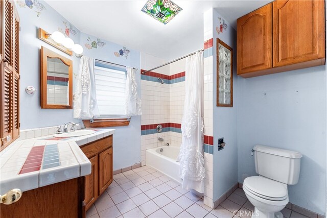 full bathroom featuring tile patterned flooring, shower / bath combo with shower curtain, vanity, and toilet