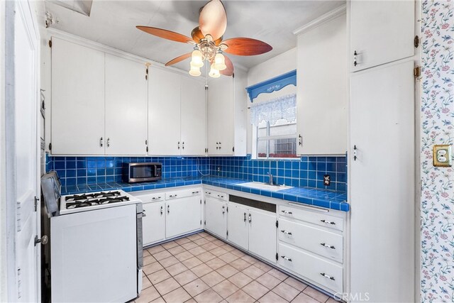 kitchen featuring tasteful backsplash, white cabinets, white stove, tile countertops, and light tile patterned floors