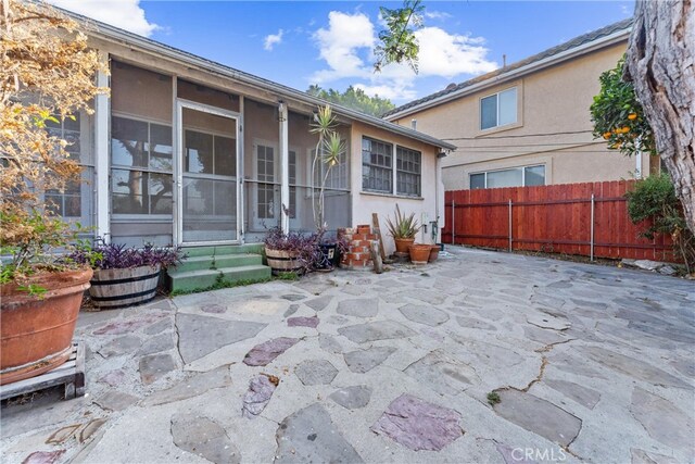 back of property with a sunroom and a patio area