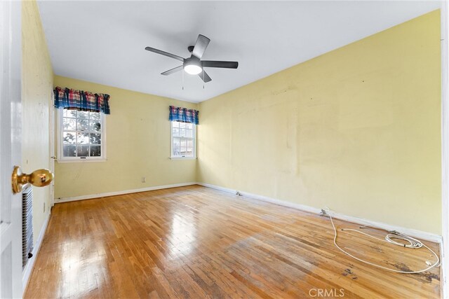 spare room featuring a healthy amount of sunlight, ceiling fan, and hardwood / wood-style floors