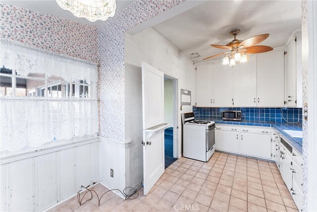 kitchen featuring ceiling fan, decorative backsplash, white cabinets, white range oven, and tile counters