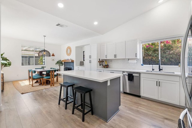 kitchen with sink, white cabinets, hanging light fixtures, and appliances with stainless steel finishes