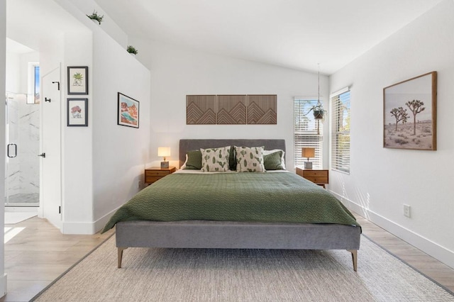 bedroom with ensuite bathroom, vaulted ceiling, and hardwood / wood-style flooring