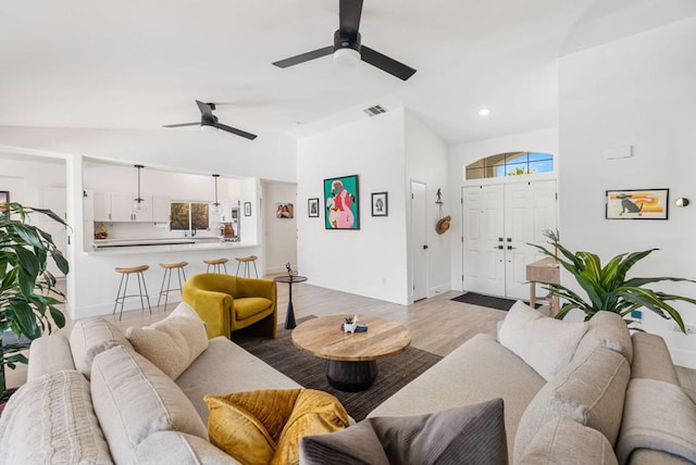 living room with vaulted ceiling, light hardwood / wood-style flooring, and ceiling fan