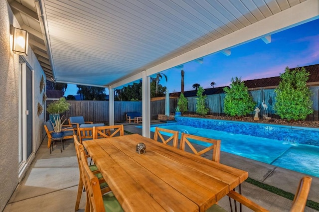 patio terrace at dusk with a fenced in pool