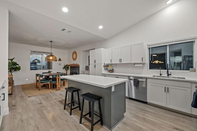 kitchen with dishwasher, lofted ceiling, sink, decorative light fixtures, and white cabinetry