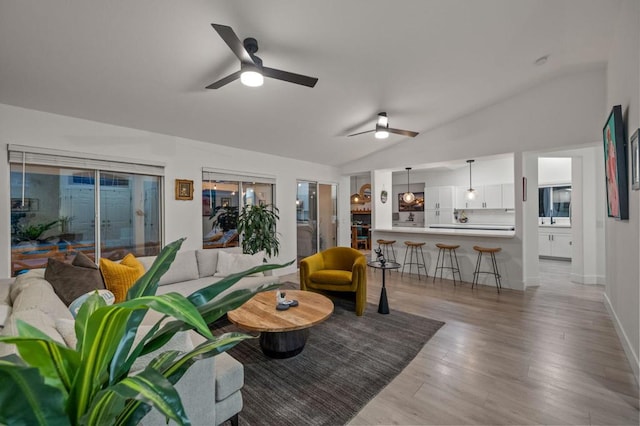 living room featuring light hardwood / wood-style flooring, vaulted ceiling, and ceiling fan