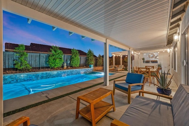 pool at dusk with pool water feature, a patio area, and an outdoor hangout area