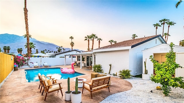 pool at dusk featuring a mountain view and a patio area